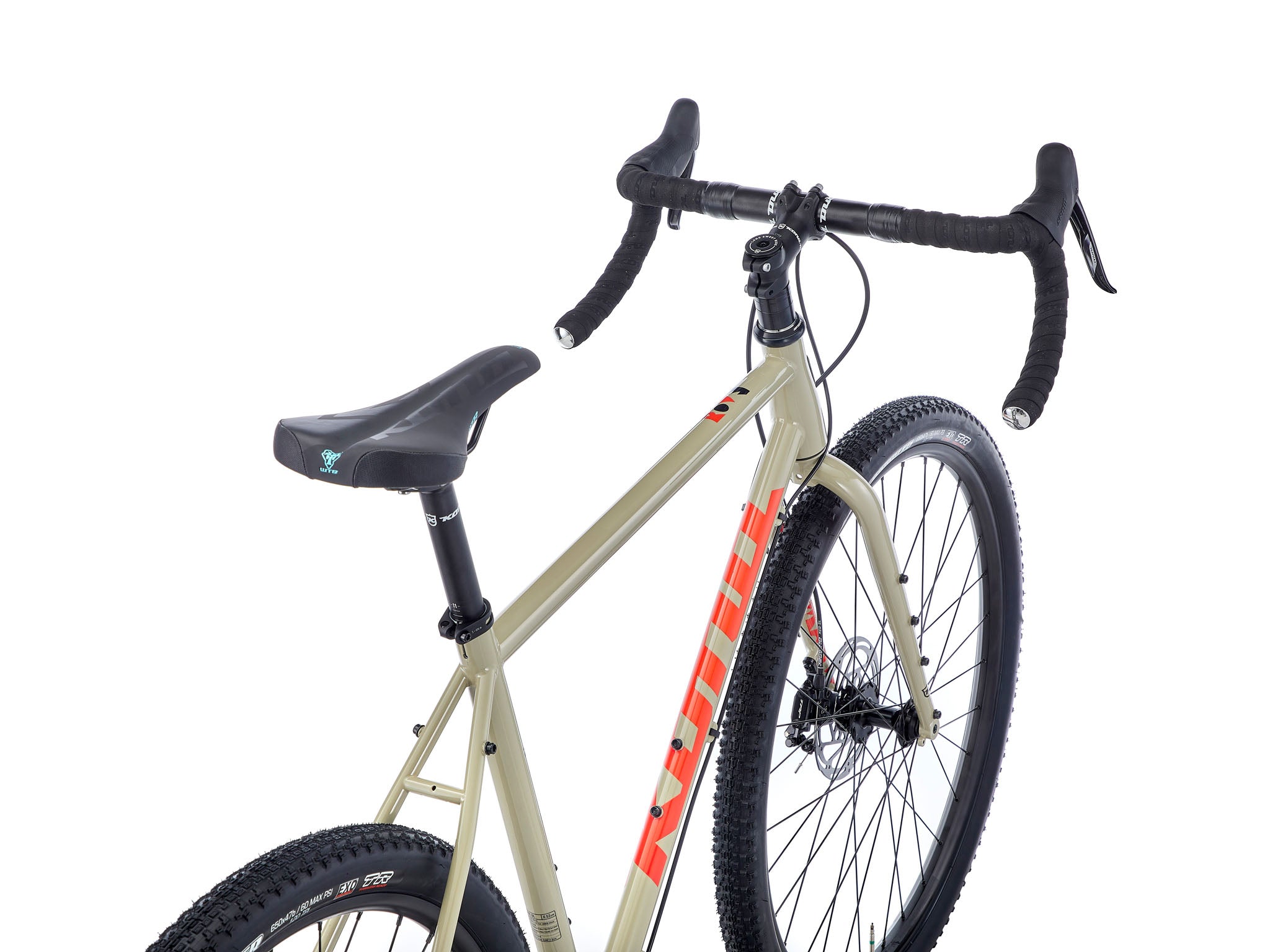 Side view of the Rove DL steel gravel bike on a forest trail, showcasing its rugged frame and all-terrain tires.